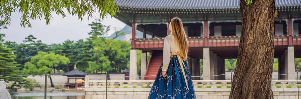Joven turista caucásica en hanbok vestido nacional coreano Viajar a Corea concepto. Ropa nacional coreana. Entretenimiento para los turistas - probándose la ropa nacional coreana BANNER, LONG FORMAT —  Fotos de Stock