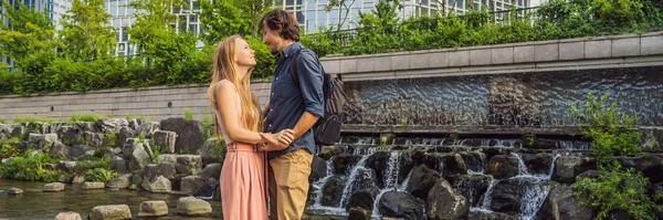 Una joven pareja enamorada pasa su luna de miel en Seúl. El arroyo Cheonggyecheon en Seúl, Corea. El arroyo Cheonggyecheon es el resultado de un proyecto masivo de renovación urbana. Viajar a Corea Concepto BANNER — Foto de Stock