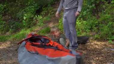 Genç bir adam ve küçük oğlu gölde ya da deniz kenarında yüzmek için şişme bir kano hazırlıyorlar.