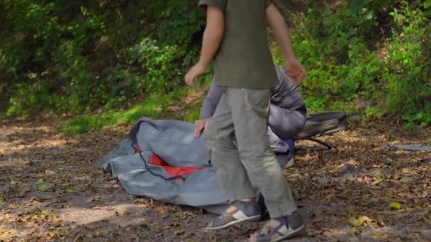 Un joven y su pequeño hijo en un lago o playa preparan un gran kayak inflable para nadar. — Vídeos de Stock