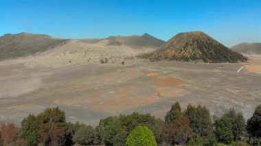Java adasındaki Tengger Kalderası 'nın içindeki ünlü aktif Bromo volkanı ya da Gunung Bromo Dağı ve Batok Yanardağı' nın hava görüntüsü. İnsansız hava aracı, köyün bulunduğu kalderanın kenarında uçuyor.