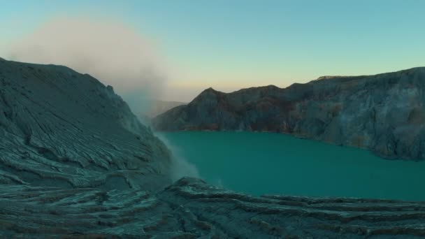 Tiro aéreo. Nascer do sol em um famoso vulcão ativo Ijen ou Kawah Ijen na ilha de Java. Sua cratera é preenchida com o maior lago ácido do mundo. E há uma mina de enxofre onde vão os gases vulcânicos. — Vídeo de Stock