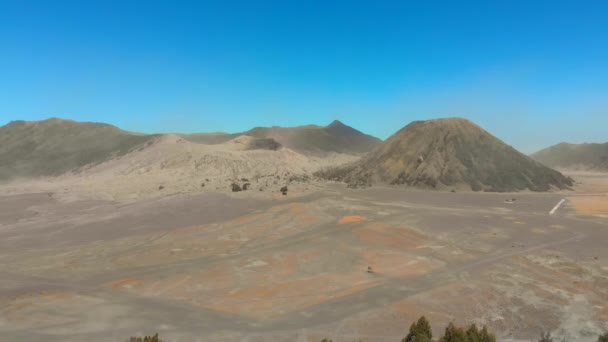 Aerial view on famous active Bromo volcano or Mount Gunung Bromo and Batok volcano inside the Tengger caldera on the Java island. Drone flies at the edge of the caldera where the village is situated — Stock Video