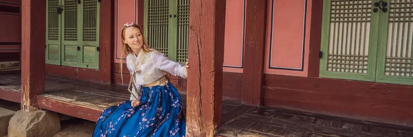 Young caucasian female tourist in hanbok national korean dress Travel to Korea concept. National Korean clothing. Entertainment for tourists - trying on national Korean clothing BANNER, LONG FORMAT