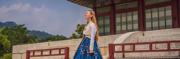 Young caucasian female tourist in hanbok national korean dress. Travel to Korea concept. National Korean clothing. Entertainment for tourists - trying on national Korean clothing BANNER, LONG FORMAT