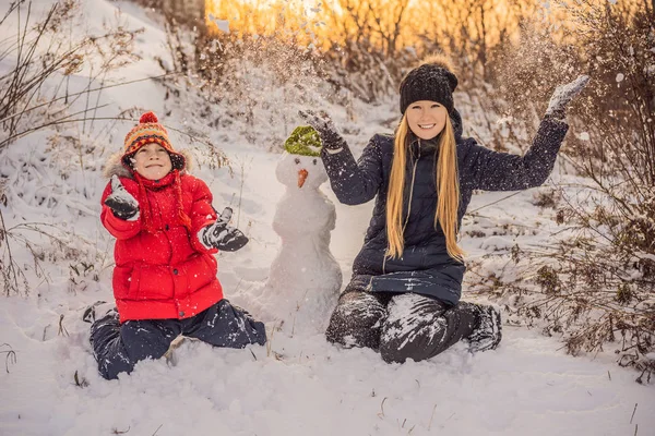 따뜻한 옷에 행복 한 가족입니다. 어머니와 아들 야외 눈사람을 만드는 미소. 겨울 활동의 개념 — 스톡 사진