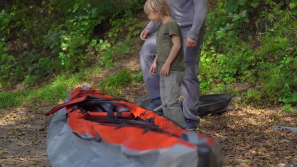 Un joven y su pequeño hijo en un lago o playa preparan un gran kayak inflable para nadar. — Vídeo de stock