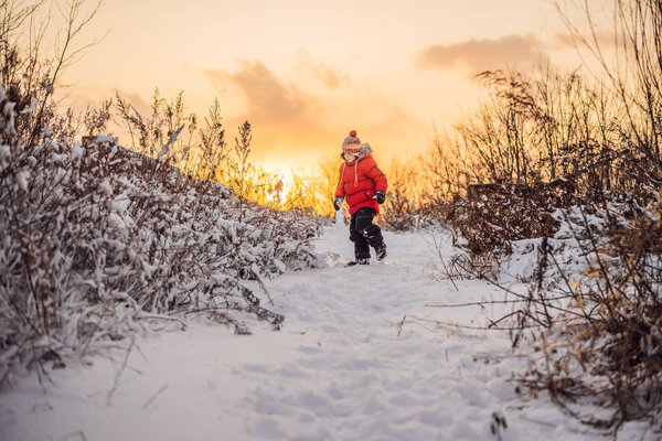 Cute boy in red winter clothes runs fun in the snow. Winter Fun Outdoor Concepts