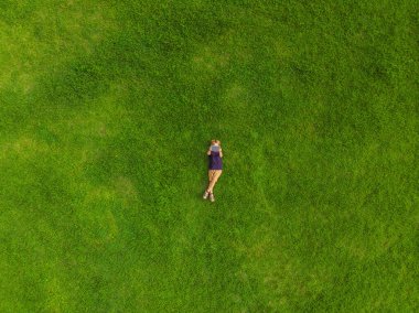 Parktaki çimlerin üzerinde yatan çocuk tablete bakıyor. Drone, quadracopter 'dan fotoğraflar