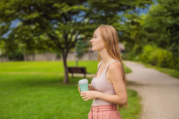 Мечтательная молодая женщина выпивает чашку кофе на улице — стоковое фото