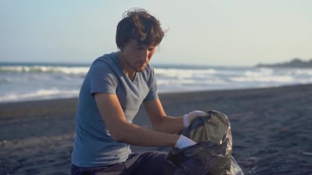 Un joven limpia la playa de una basura — Vídeos de Stock