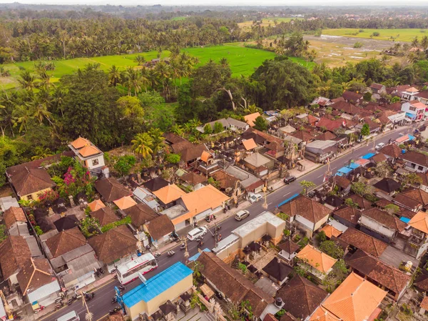 Mange villaer med brun-orange rullesten tage mellem tropiske træer på himlen baggrund i Ubud på Bali. Solen skinner på dem. Luftvandret foto - Stock-foto