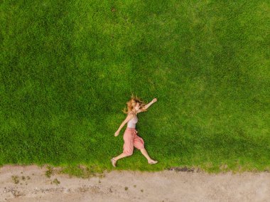 Genç bir kadın bir tarlanın ortasında uzanıyor ve rahatlıyor.