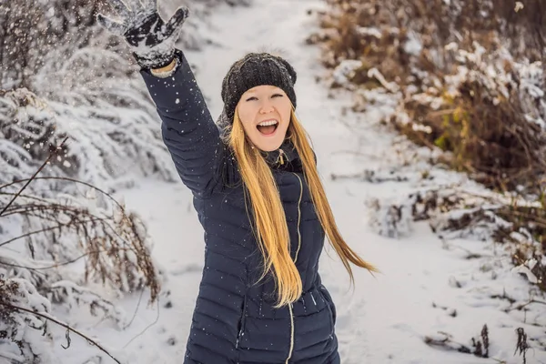 Wintermädchen werfen Schneeball in die Kamera lächelnd glücklich Spaß im Freien an einem verschneiten Wintertag im Schnee spielen. niedliche verspielte junge Frau im Freien genießt ersten Schnee — Stockfoto