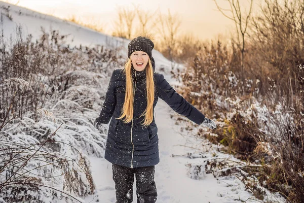 Zimní dívka házet sněhovou kouli na kameru s úsměvem šťastný baví venku na sněhu zimní den hraje ve sněhu. Roztomilý hravý mladý žena venkovní těší první sníh — Stock fotografie