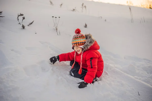 Boy in red fashion clothes playing outdoors. Active leisure with children in winter on cold days. Boy having fun with first snow. Happy little kid is playing in snow, good winter weather — Stock Photo, Image