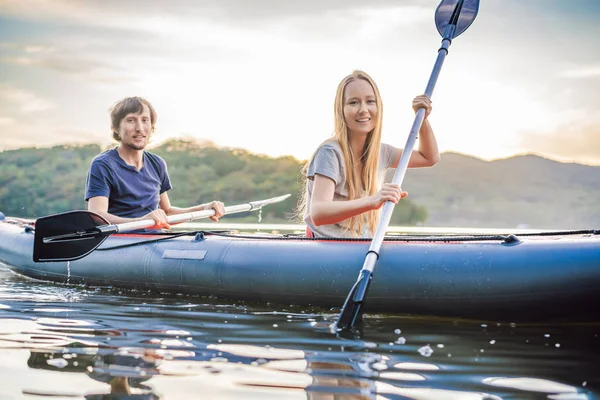L'uomo e la donna nuotano sul kayak in mare sullo sfondo dell'isola. Concetto di kayaking.Concetto di kayak con famiglia di madre di padre in mare — Foto Stock