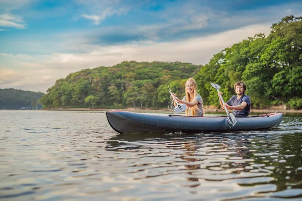 Férfiak és nők úszkálnak a kajakon a tengerben a sziget hátterében. Kayaking koncepció.Kayaking koncepció a család apa anya a tengeren — Stock Fotó