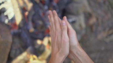 Soğuk bir sonbahar ormanında şenlik ateşinin yanında oturan genç adam. Sonbahar tatili kavramı