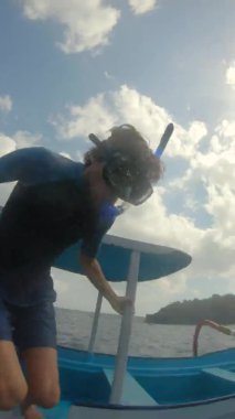 Dalgıç maskeli bir adam Nusa Penida Adası 'ndaki Manta Noktası' nda manta görmek için tekneden denize atlıyor.