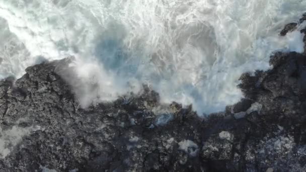 黒い火山ビーチの空中ショット。自然噴水の出現を引き起こす岩の上で波がクラッシュ — ストック動画
