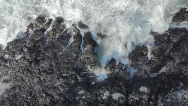 Εναέρια λήψη μαύρης ηφαιστειακής παραλίας. Κύματα πέφτουν στους βράχους προκαλώντας την εμφάνιση φυσικών συντριβανιών. — Αρχείο Βίντεο