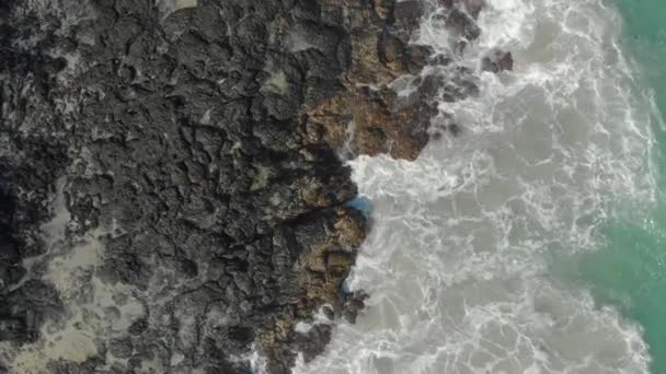 Foto aérea de una playa negra volcánica. Olas chocan contra las rocas causando la aparición de fuentes naturales — Vídeos de Stock