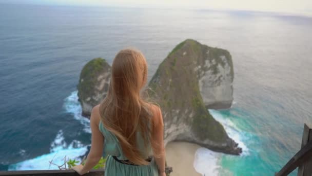 Jovem turista visita a chamada rocha Tyrannosaur na Praia Kelingking, Nusa Penida, Indonésia. Famoso lugar turístico na ilha de Nusa Penida. Tiro em câmara lenta — Vídeo de Stock