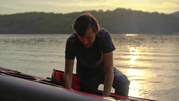 Young man inflates his kayak and prepares it for paddling in a lake or sea. Slowmotion shot — Stock Video