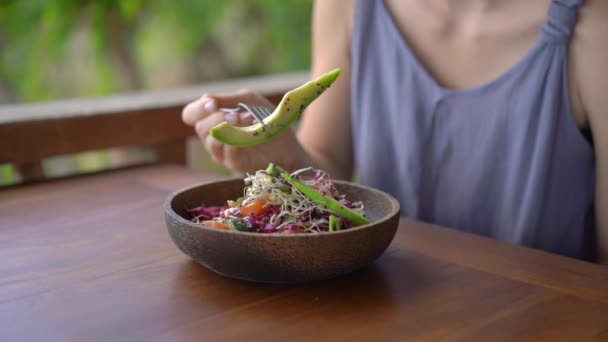 Una giovane donna in un caffè tropicale mangia sana insalata vegetariana. Concetto di cibo vegano. Colpo di rallentamento — Video Stock