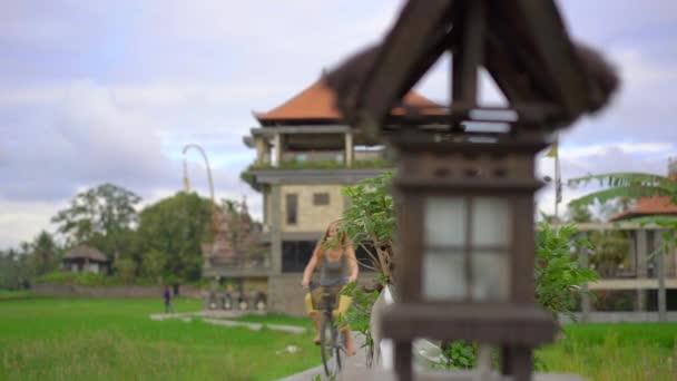 Eine junge Frau fährt mit dem Fahrrad durch das schöne Reisfeld. Reise nach Südostasien. Zeitlupenaufnahme — Stockvideo