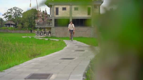 Un joven pasea por el hermoso campo de arroz en bicicleta. Viaje al concepto del sudeste asiático. Disparo en cámara lenta — Vídeo de stock