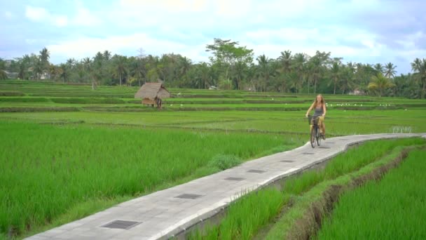 Молодая женщина и ее маленький сын едут по красивому рисовому полю на велосипеде. Путешествие в Юго-Восточную Азию. Медленный выстрел — стоковое видео
