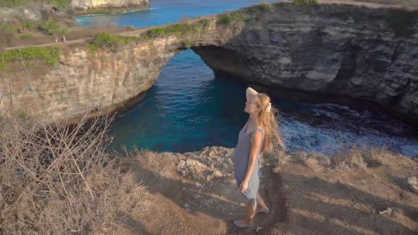 Jonge vrouw toerist bezoekt het Broken Beach, beroemde toeristische locatie op het Nusa Penida eiland, Indonesië. Reis naar Indonesië concept — Stockvideo
