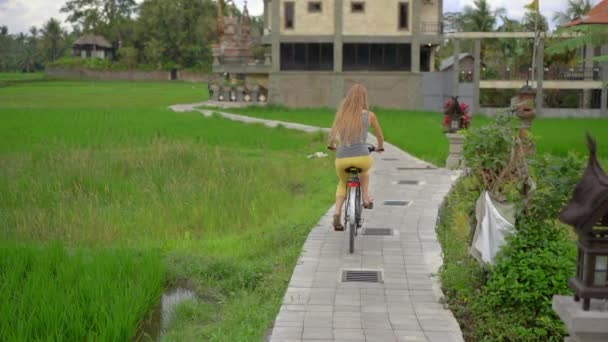 Una joven cabalga a través del hermoso campo de arroz en bicicleta. Viaje al concepto del sudeste asiático. Disparo en cámara lenta — Vídeos de Stock