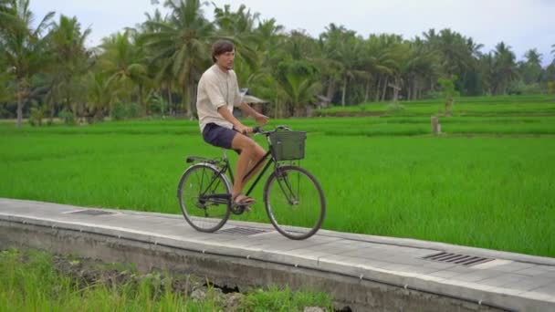 Un joven pasea por el hermoso campo de arroz en bicicleta. Viaje al concepto del sudeste asiático. Disparo en cámara lenta — Vídeos de Stock