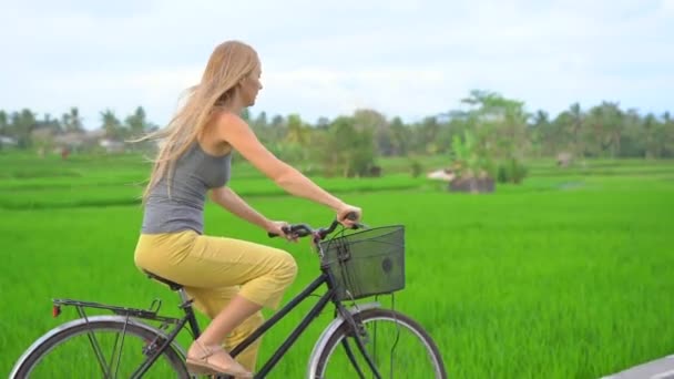 한 젊은 여자가 아름다운 논을 자전거로 통과 한다. 동남아 지역으로 여행을 떠났습니다. 느린 모션 샷 — 비디오
