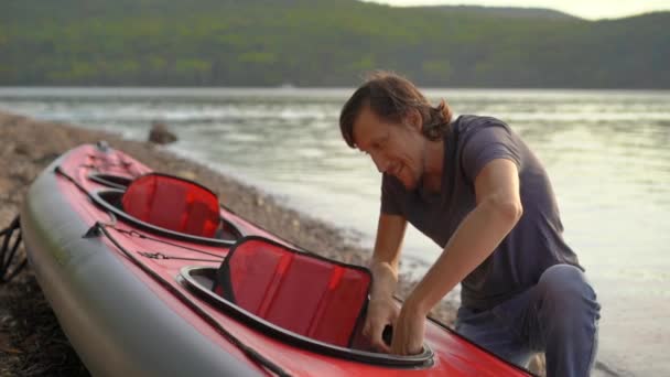 El joven infla su kayak y lo prepara para remar en un lago o mar. Disparo en cámara lenta — Vídeos de Stock