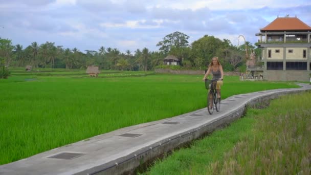 En ung kvinna rider genom det vackra risfältet på en cykel. Res till Sydostasien. Långsam rörelse skott — Stockvideo