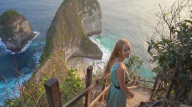 Genç bayan turist, Endonezya 'nın Kelingking Plajı' ndaki sözde Tyrannosaur kayası olan Nusa Penida 'da yaşıyor. Nusa Penida adasındaki ünlü turistik yer. Yavaş çekim.
