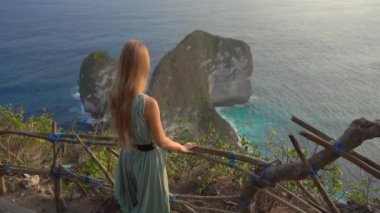 Genç bayan turist, Endonezya 'daki Kelingking Sahili' ndeki Tyrannosaur kayasını ziyaret ediyor. Nusa Penida adasındaki ünlü turistik yer. Yavaş çekim.