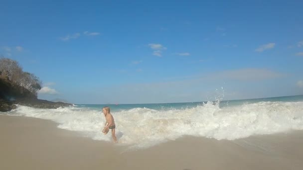 Медленный снимок маленького мальчика, веселящегося на тропическом пляже. Летняя концепция — стоковое видео