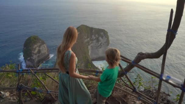 这名年轻女子和她的小儿子游客参观了位于印度尼西亚努沙佩尼达Kelingking海滩的所谓的Tyrannosaur岩石。 努沙佩尼达岛上著名的旅游胜地。 慢动作射击 — 图库视频影像