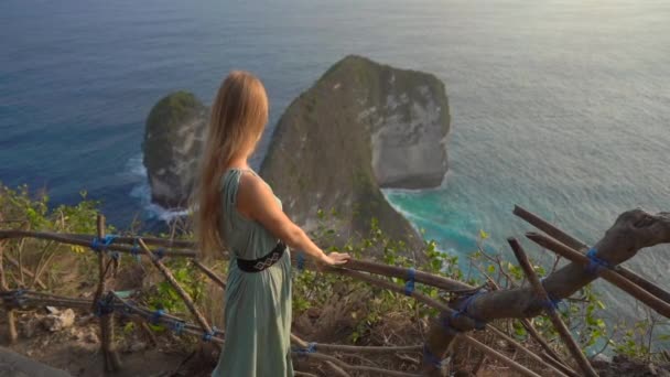 Una joven turista visita la llamada roca Tiranosaurio en Kelingking Beach, Nusa Penida, Indonesia. Famoso lugar turístico en la isla de Nusa Penida. Disparo en cámara lenta — Vídeos de Stock
