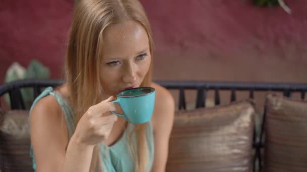 Jonge vrouw geniet van blauwe latte zittend in een prachtig café. Hete vlinder erwt latte of blauwe spirulina latte. Langzame schot. — Stockvideo