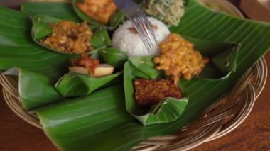 Genç adam ve küçük oğlu geleneksel Bali yemekleri yiyorlar Nasi Campur 'da geleneksel bir kafede. Bali konseptine Seyahat