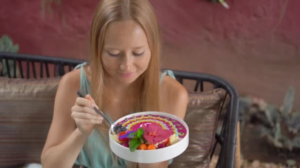 Young woman enjoy colorful granola smoothie in the bowl sitting in a beautiful cafe. Healthy eating concept. Slowmotion shot — ストック動画