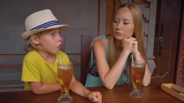Genç bir kadın ve küçük oğlu geleneksel bir kafe olan Nasi Campur 'da geleneksel Bali yemekleri yiyorlar. Bali konseptine Seyahat