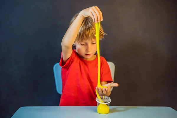 Niño jugando juguete hecho a mano llamado limo. Un niño juega con limo. Chico exprimir y estirar limo — Foto de Stock