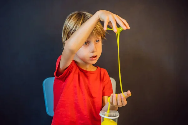 Niño jugando juguete hecho a mano llamado limo. Un niño juega con limo. Chico exprimir y estirar limo — Foto de Stock